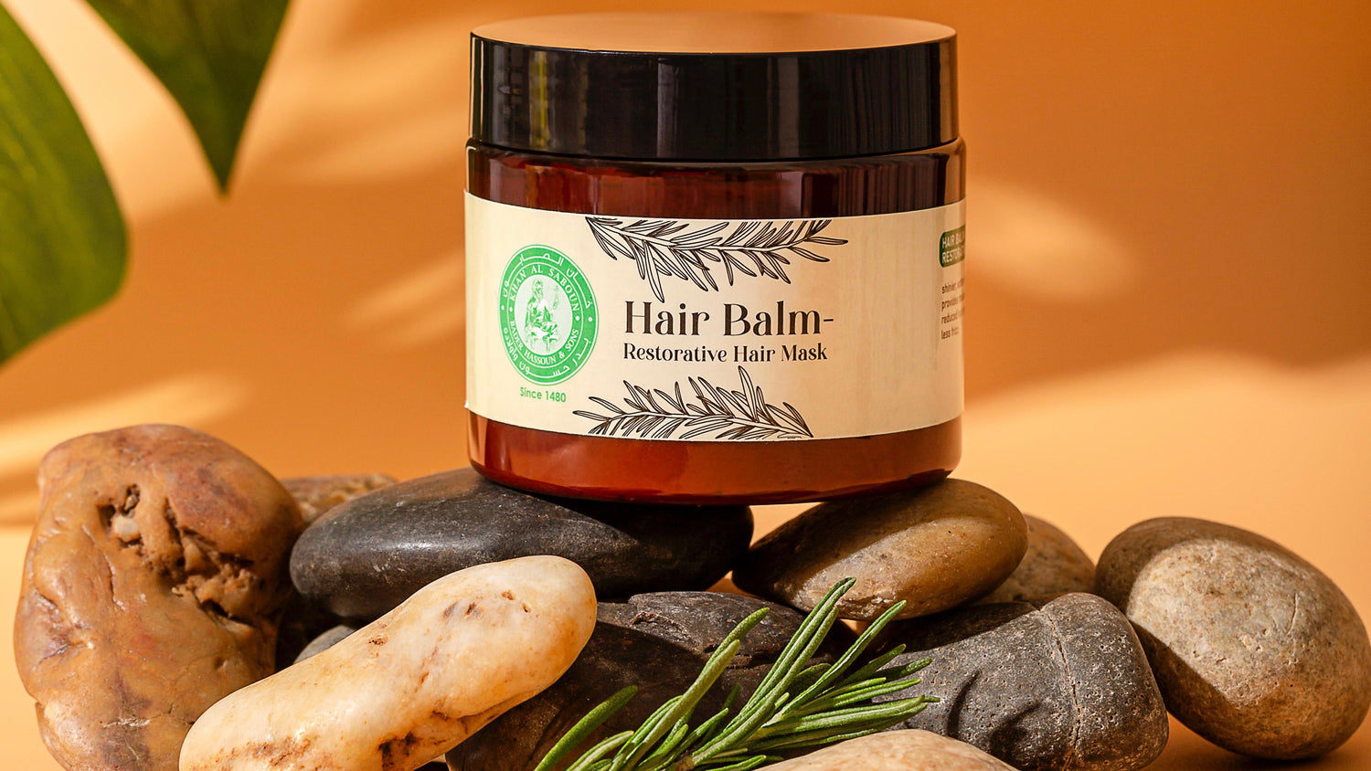 Hair balm jar with label on rocks and leaves
